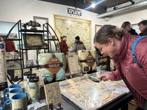 Woman looking through the Xplorer Maps book at Headquarters with products in the background.