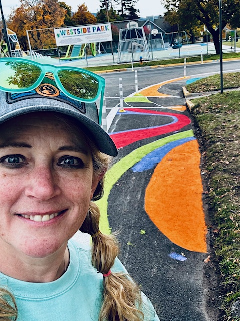 Artist standing in front of her street mural for Lowell School Mural Project