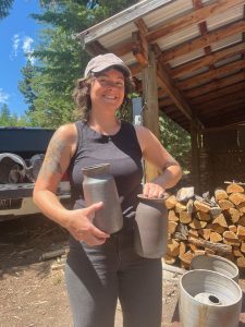 Person holding two vases with wood stacked in background