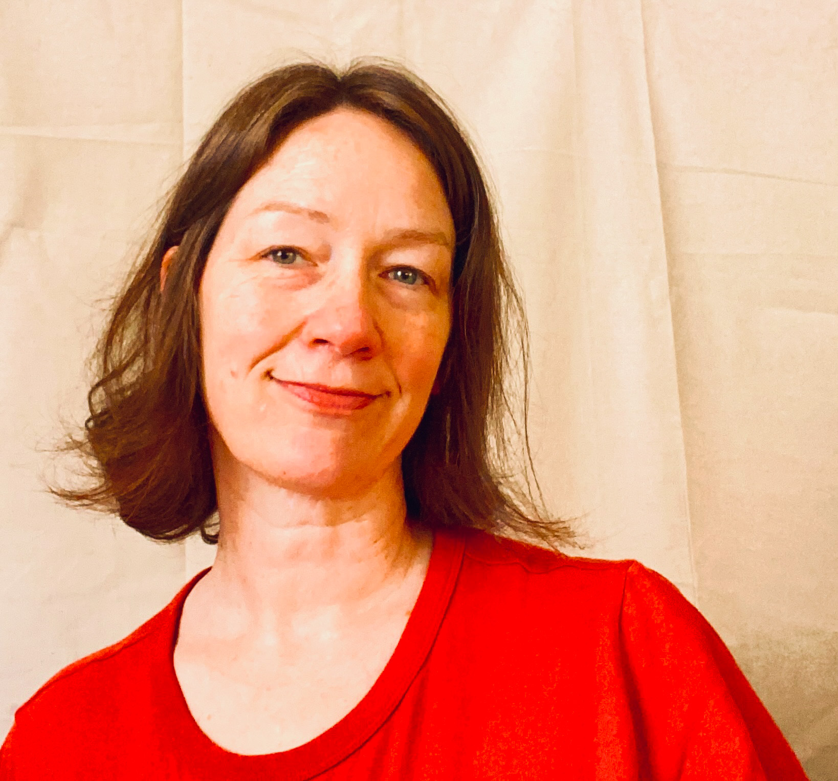 a white woman in a bright red shirt kind of smiles