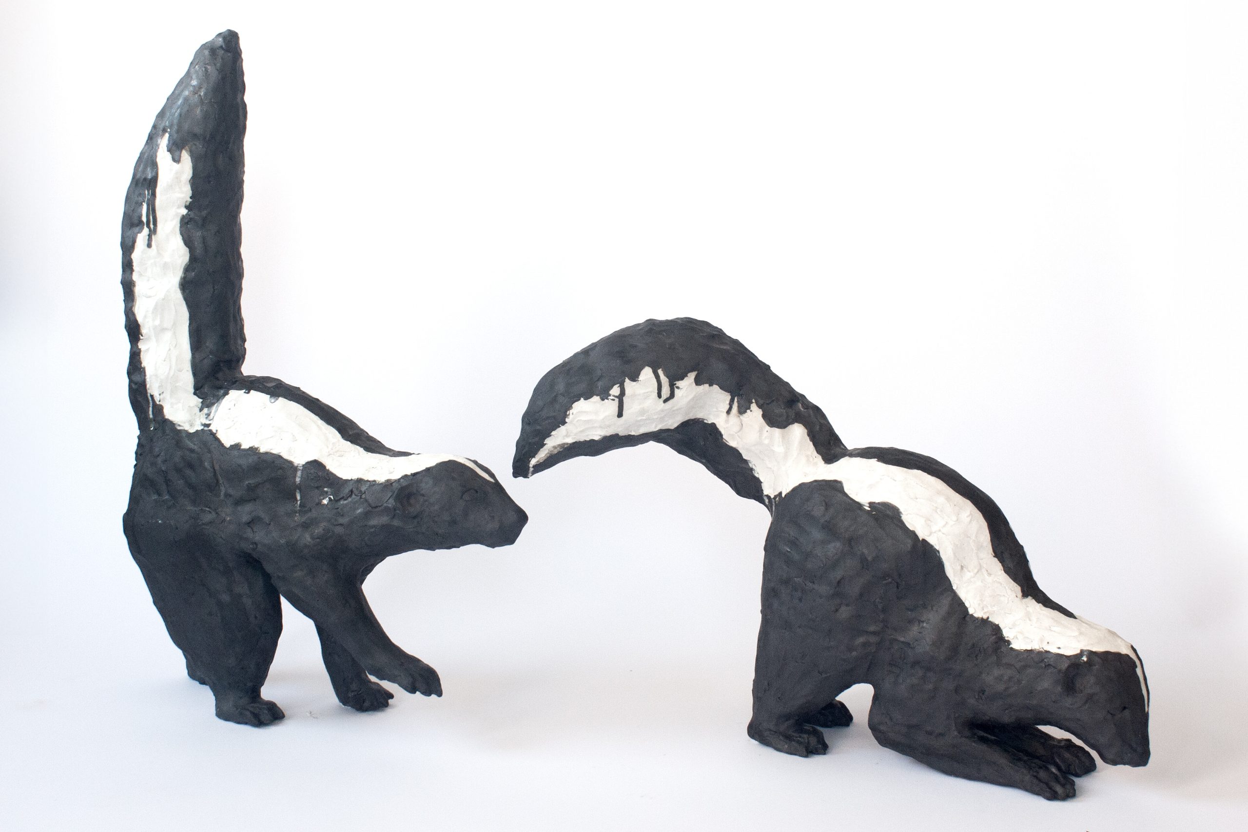 a sculpture of two ceramic skunks